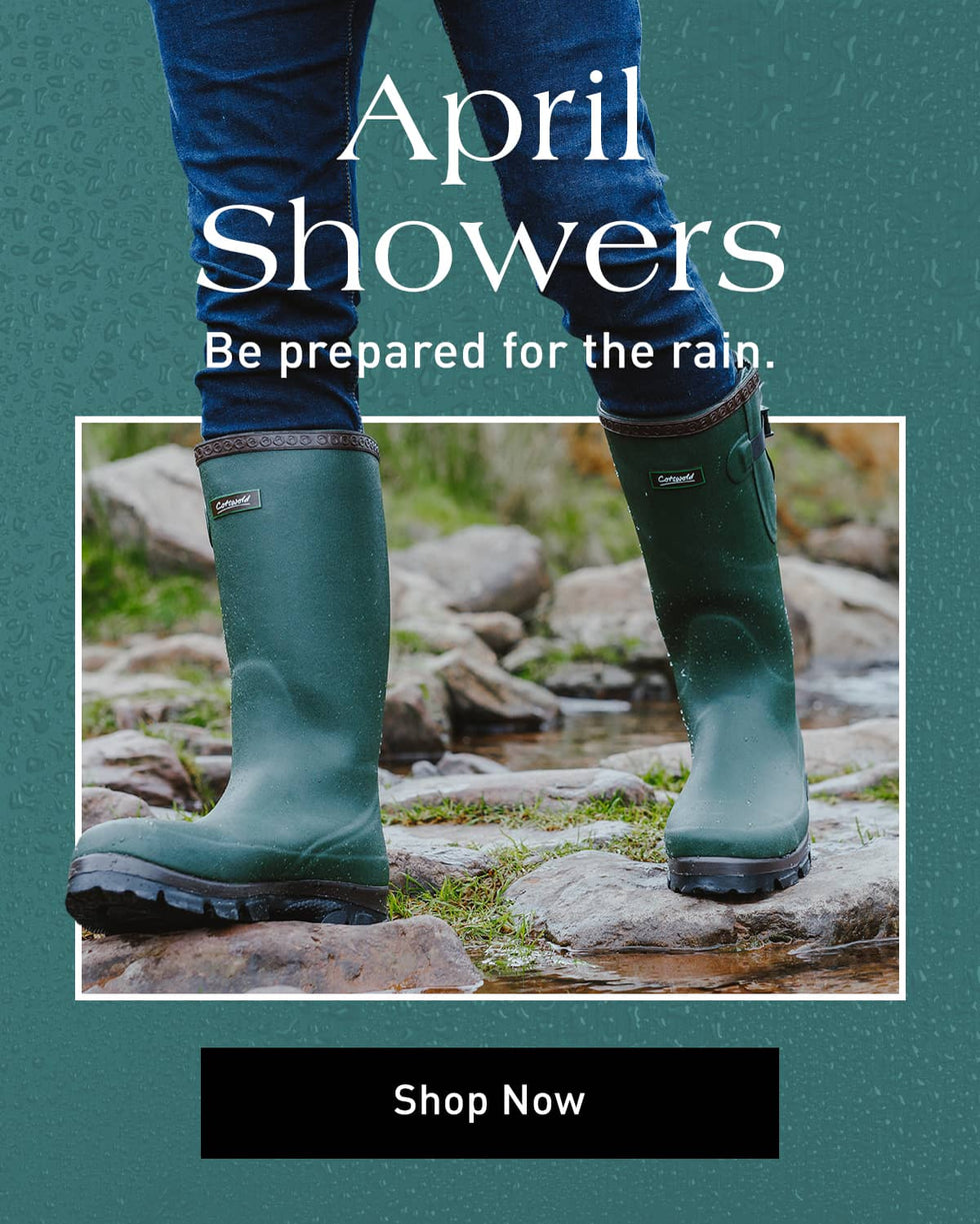 Green rubber boots on rocks with text 'April Showers Be prepared for the rain. Shop Now' on a teal background